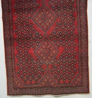 A contemporary Persian carpet with red ground and geometric designs 85" x 62"