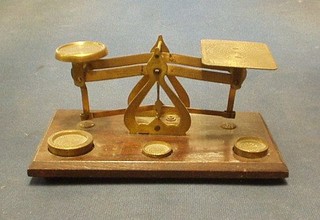 A pair of brass letter scales, raised on a wooden base