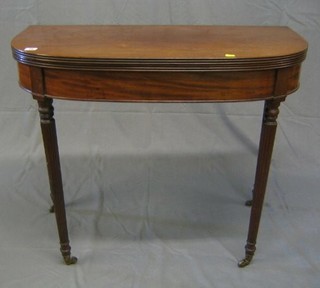 A 19th Century mahogany demi-lune card table raised on turned and reeded supports ending in brass caps and castors 36"