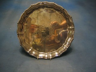 A circular silver plated salver with gadrooned and bracketed border, raised on 3 hoof feet 12"