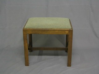 A Georgian style mahogany stool with upholstered drop in seat, raised on an H framed stretcher