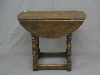 A pair of oak oval drop flap occasional tables raised on turned and block supports 27"