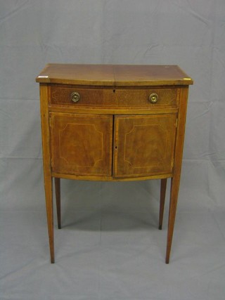 An Edwardian inlaid mahogany bow front sewing box with hinged lid and fitted interior, the base fitted a double cupboard enclosed by panelled door, raised on square tapering supports 21"