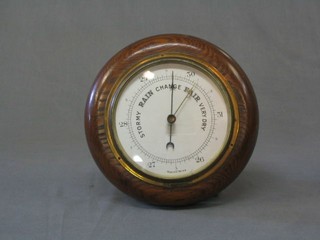 An aneroid barometer with silvered dial contained in an oak case