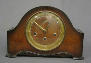 A 1950's walnutwood striking mantel clock with Arabic numerals contained in an oak arch shaped case