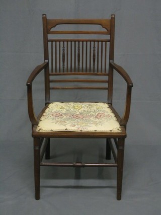 An Edwardian mahogany stick and rail back open arm chair raised on turned supports