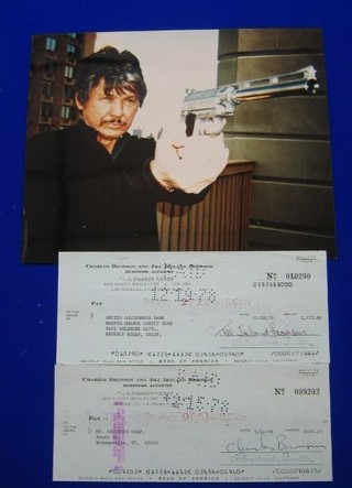 A cheque dated 1978, signed by Charles Bronson, together with a cheque signed by his wife Jill Ireland and a colour photograph of Bronson from the film Death Wish