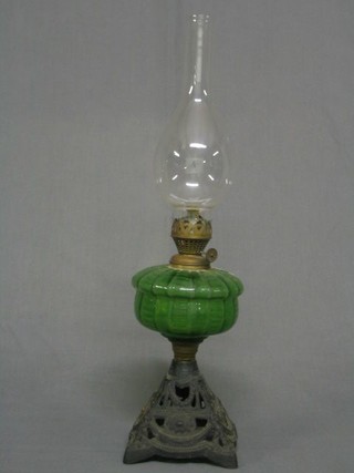 A Victorian oil lamp with green glass reservoir, raised on a pierced iron stand