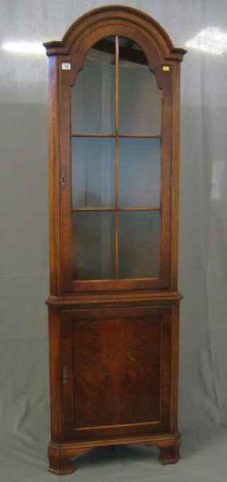 A Queen Anne style walnutwood double corner cabinet of arched shape, the upper section fitted shelves enclosed by a panelled door 23"