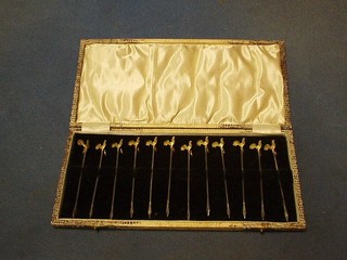 A set of 12 silver and silver gilt cocktail sticks, the heads in the form of cockerels, Birmingham 1928, cased