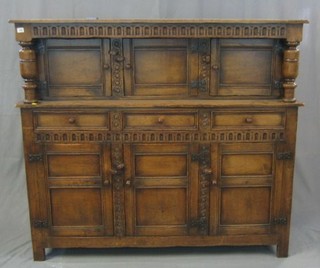 A carved oak court cupboard fitted 3 panelled doors, the base fitted 3 drawers 60"
