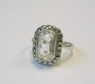 A lady's silver dress ring set a rectangular white cut stone supported by  marcasites