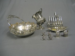 A Victorian Britannia metal sugar scuttle, 2 silver plated toast racks, a pierced silver plated cake basket, a pair of knife rests, a lady's compact and a salt and pepper