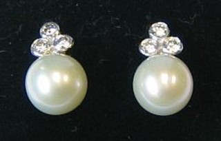 A pair of lady's pearl ear studs surmounted by 3 diamonds
