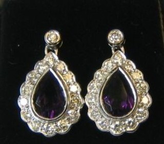 A pair of lady's tear drop earrings set amethysts surrounded by 14 diamonds