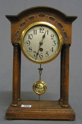 A 1920's 8 day mantel clock with silvered dial and Arabic numerals contained in an oak arched case