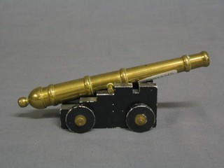 A brass model canon with 6 1/2" barrel, raised on a metal stepped trunion