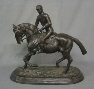 A bronze figure of a race horse with jockey up, raised on an oval naturalistic base 17"