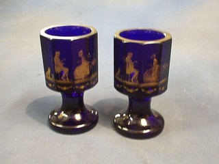 A pair of 19th Century Bohemian octagonal blue glass goblets decorated tea drinking scenes and raised on circular spreading feet 6 1/2"