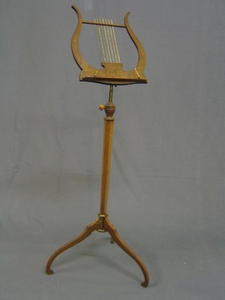 A 19th Century inlaid rosewood music stand in the form of a lyre decorated musical trophies and raised on an octagonal column and tripod support