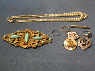 A gilt metal belt buckle, 2 strings of cultured pearls, a Royal Artillery sweet heart's brooch, a silver Scots clan brooch, 3 rings, a bar brooch, an enamelled brooch