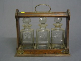 An oak and silver plated tantalus frame with 3 cut glass spirit decanters