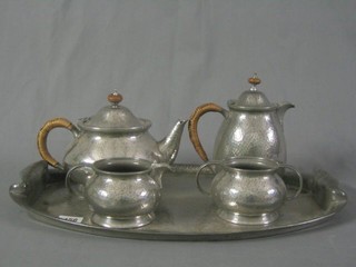 An Art Nouveau Tudric 5 piece planished pewter tea service comprising twin handled tea tray, teapot, hotwater jug, sugar bowl and cream jug, the base marked 10075