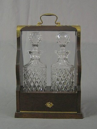 A modern mahogany and brass banded 2 bottle tantalus fitted 2 cut glass spirit decanters