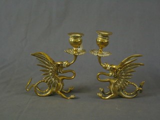 A pair of brass candlesticks in the form of griffings