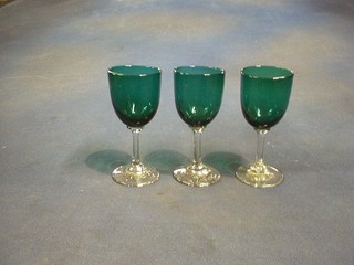A set of 3 green glass wine glasses with clear glass stems