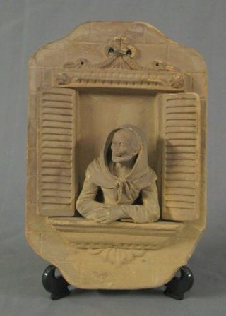 A 19th Century Italian terracotta plaque in the form a lady leaning out of a shuttered open window 11"
