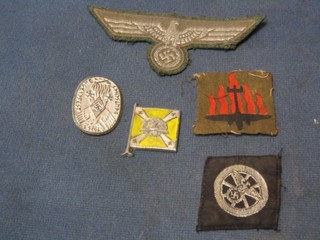 An embossed Nazi badge marked 1935, 3 Nazi cloth badges and a plastic Nazi pennant