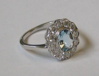A lady's attractive 18ct white gold dress ring set an oval cut aquamarine surrounded by 12 diamonds (approx 0.72/1ct)