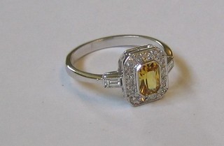 A lady's 18ct white gold dress ring set a rectangular cut yellow sapphire surrounded by numerous diamonds and diamonds to the shoulders