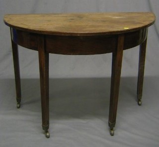 A 19th Century mahogany demi-lune table raised on pillar and tripod supports ending in brass caps and castors 42"