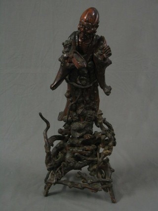 A large 19th Century Oriental carved rootwood figure of a standing Deity raised on a pierced stand 38"