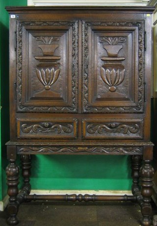 A fine quality 19th Century carved oak cabinet on stand, the upper section with cupboard enclosed by panelled doors, the base fitted 2 drawers and raised on a carved base with H framed stretcher and bulbous supports 45"