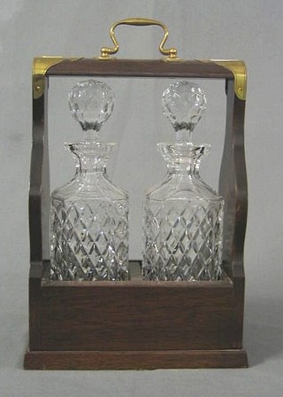A modern mahogany and brass banded 2 bottle tantalus fitted 2 cut glass spirit decanters