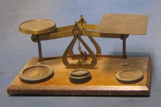 A pair of brass letter scales raised on an oak base together with weights