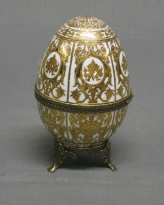 A modern Sevres style porcelain egg with gilt decoration and metal mounts