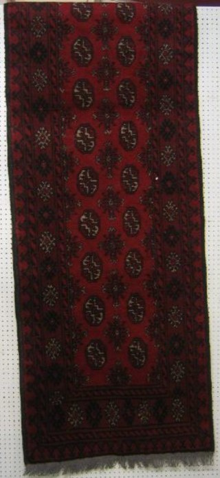 A contemporary red ground Afghan runner with 26 octagons to the centre 108" x 30"