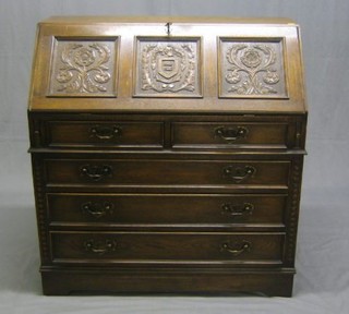 An oak fall front bureau above 4 long graduated drawers, the fall front being carved with 3 panels decorated the Brighton Shield" Estimate