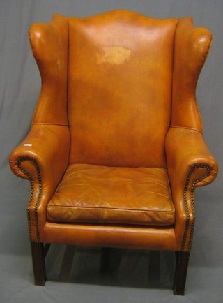 A Georgian style mahogany winged arm chair upholstered in orange hide