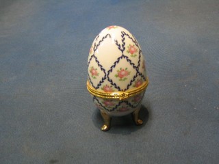 An egg shaped porcelain trinket box with floral decoration and hinged lid