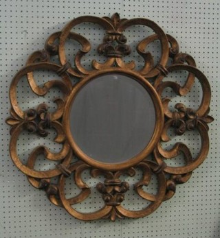 A circular plate wall mirror contained in a pierced gilt frame