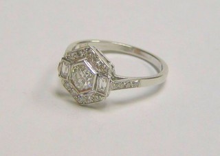 A lady's 18ct white gold Art Deco style dress ring, set an octagonal cut diamond supported by 2 baguette cut diamonds and numerous other diamonds and having 8 diamonds to the shoulders (approx 0.85ct)