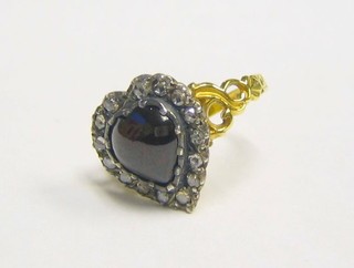 A lady's gold dress ring set a cabouchon cut heart shaped garnet surrounded by diamonds