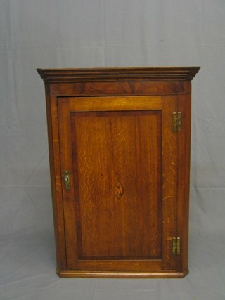 A Georgian oak hanging corner cabinet with moulded cornice, the interior fitted shelves enclosed by a panelled door with crossbanded and inlaid panel 28"