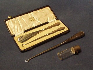 A silver handled button hook and a silver handled shoe horn and button hook cased and a glass salts bottle with hinged silver lid