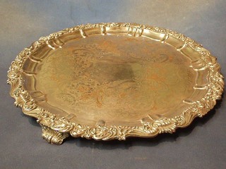 A large circular silver plated salver with engraved decoration and bracketed border, raised on 3 scroll feet 18"